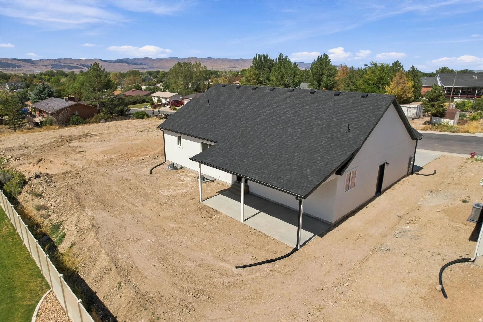 Newly constructed residence with a dark shingle roof, white exterior siding, and a covered concrete patio