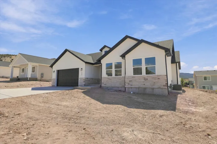 Contemporary exterior with a white stucco finish, stone veneer accents, dark trim, a dark garage door, and a concrete driveway