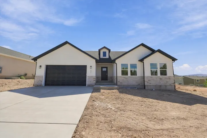 White stucco exterior with stone accents, black roof, and dark garage door