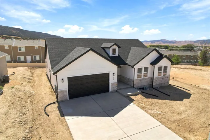 Contemporary exterior featuring white siding, stone veneer accents, dark trim, a two-car garage, and a concrete driveway