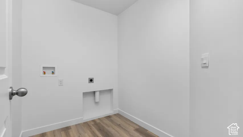 Dedicated laundry area featuring wood-finish flooring, white walls, and essential utility hookups