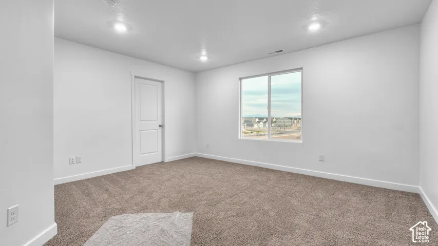 Recessed lighting, neutral paint palette, brown carpeting, white trim, and a window with a distant landscape