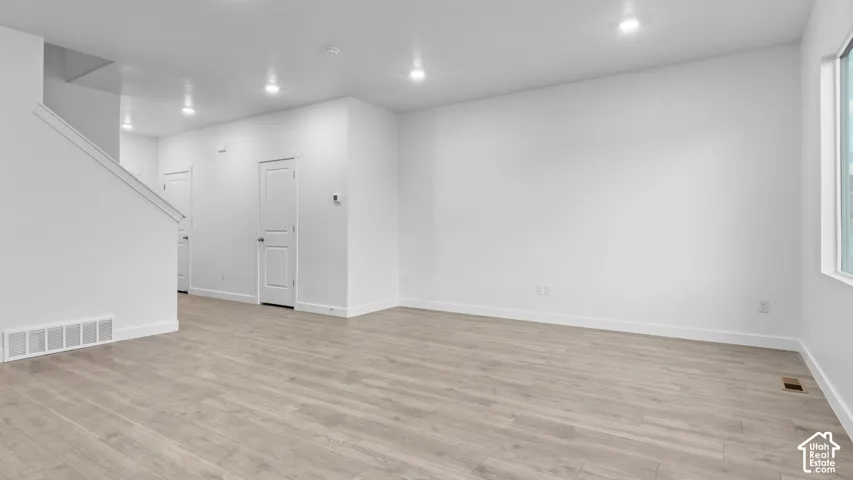 Recessed ceiling lighting, durable wood-finish flooring, white painted walls, and a large window