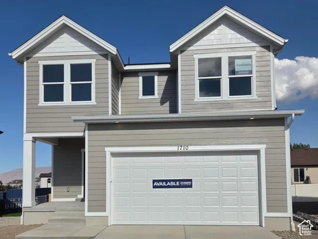 Two-story residence featuring light gray horizontal siding, white trim, and a prominent two-car garage