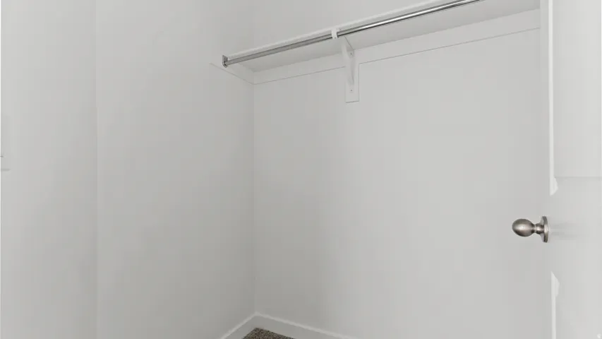 Minimalist closet featuring a built-in shelf and metal hanging rod