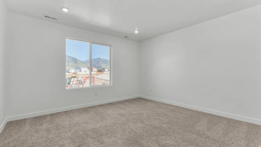 Recessed lighting, neutral wall tones, large window, mountain backdrop, and carpet flooring