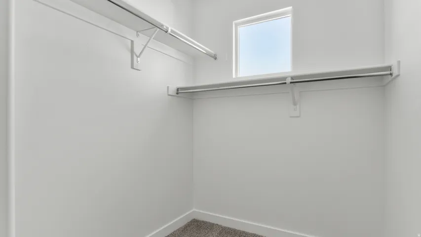 Walk-in closet featuring a window, built-in shelving, and hanging rods