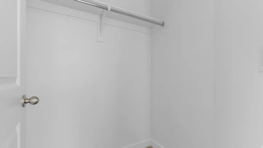 Closet featuring a metal hanging rod with shelf and white walls