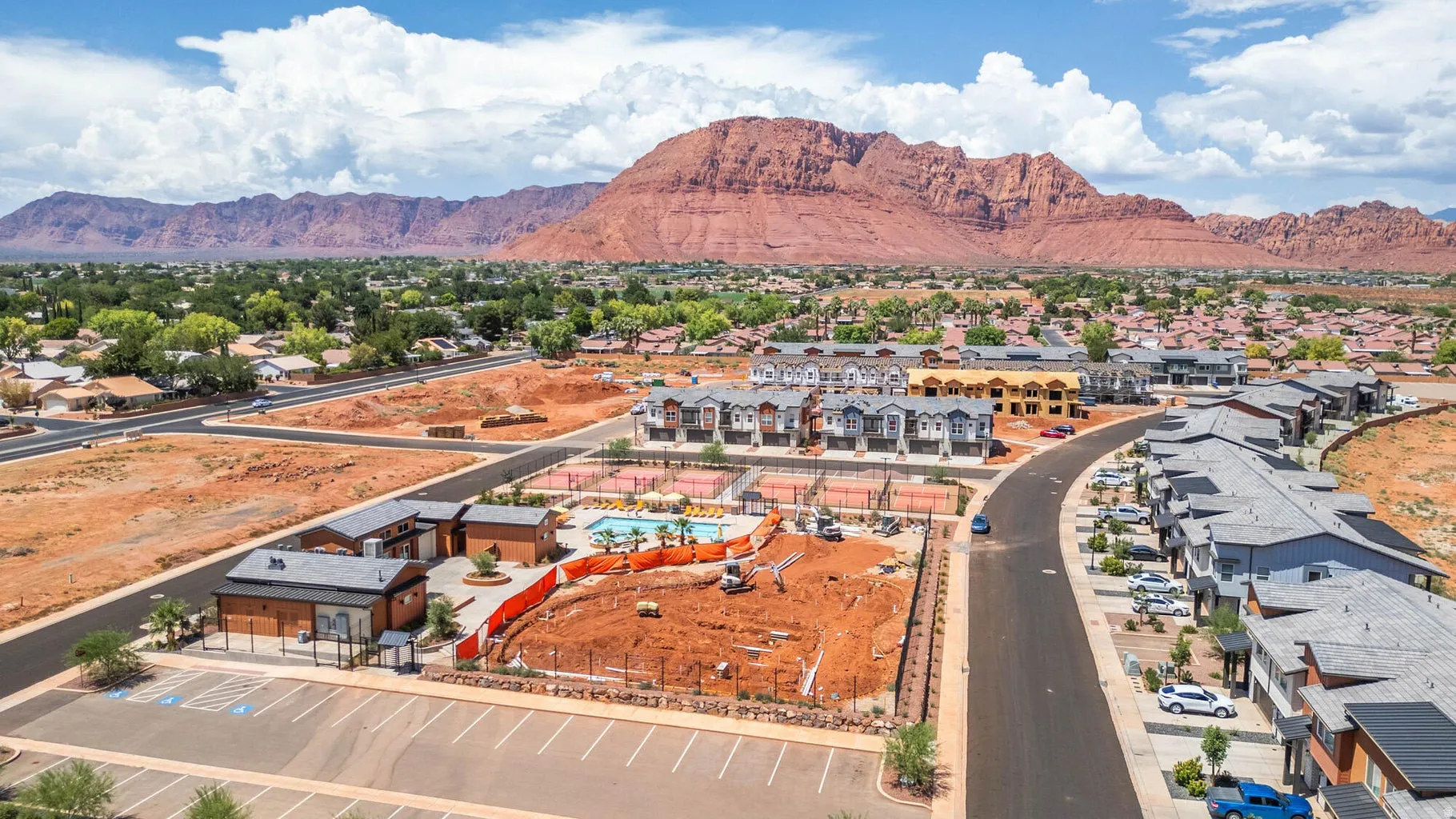 Newly constructed community featuring a swimming pool, multiple tennis courts, and a parking area with marked spaces