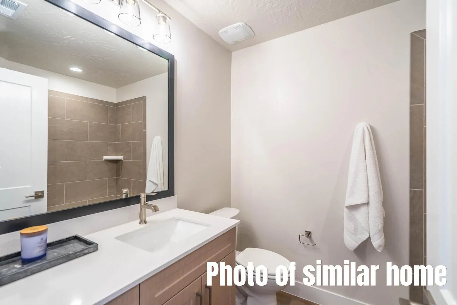 Vanity with a rectangular sink, brushed nickel faucet, large mirror, and overhead lighting