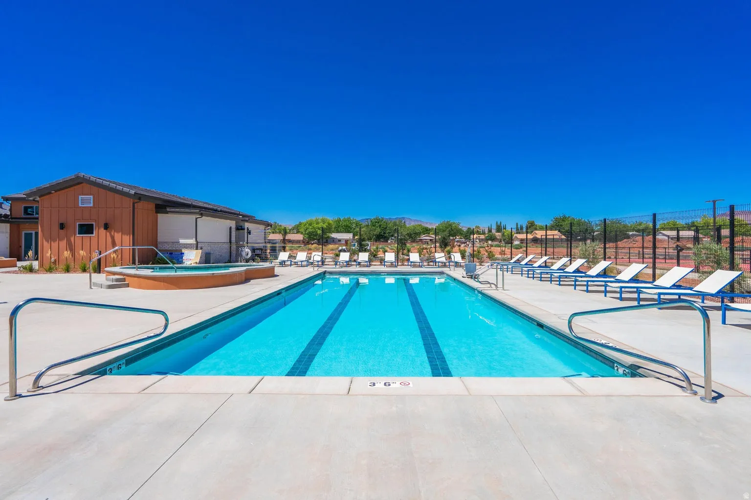 Outdoor swimming pool with integrated lane lines, concrete decking, and an adjacent hot tub