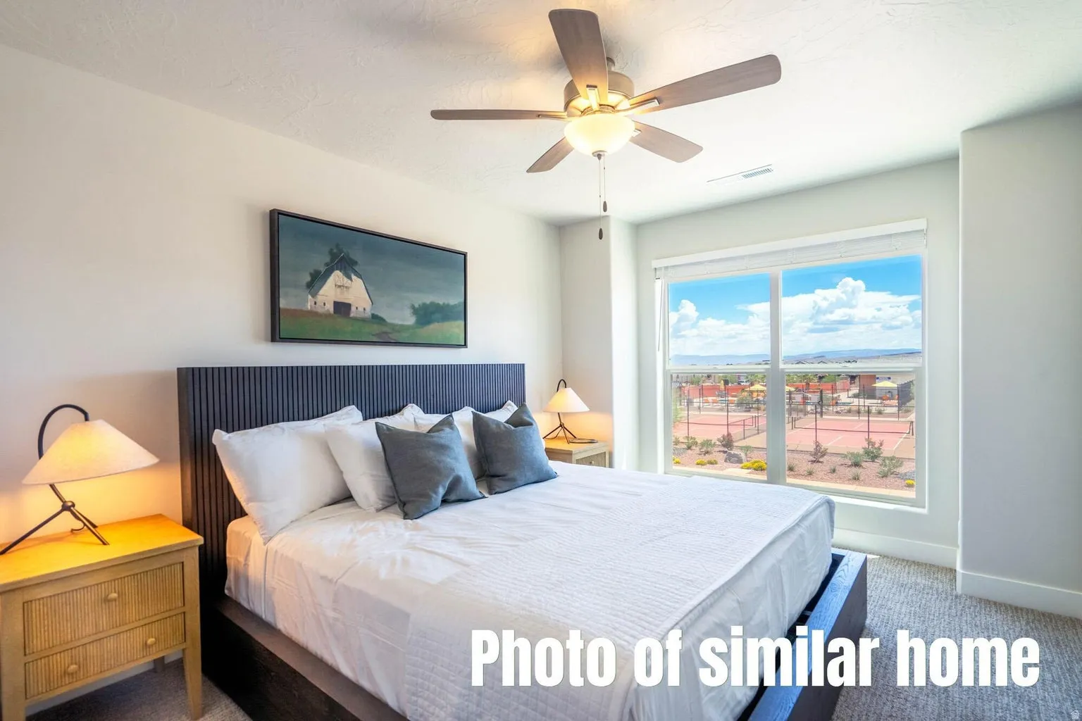 Large window with roller shade, ceiling fan with integrated lighting, textured wall finish, and carpeted flooring