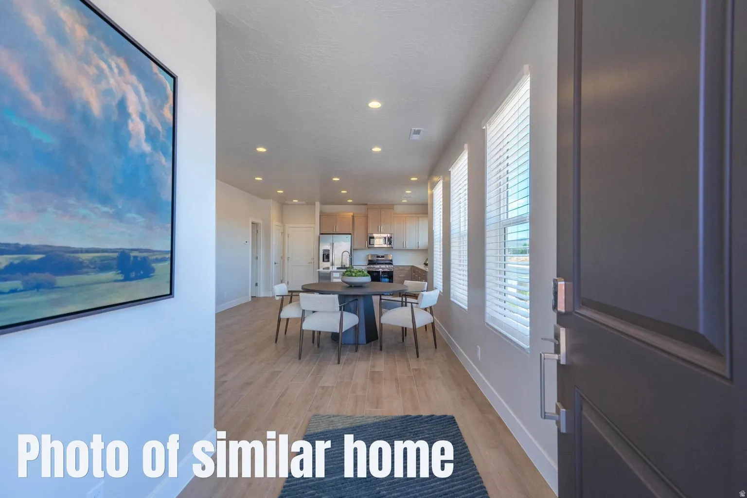 Open-concept living space featuring wood-finish flooring, recessed lighting, and multiple windows with blinds