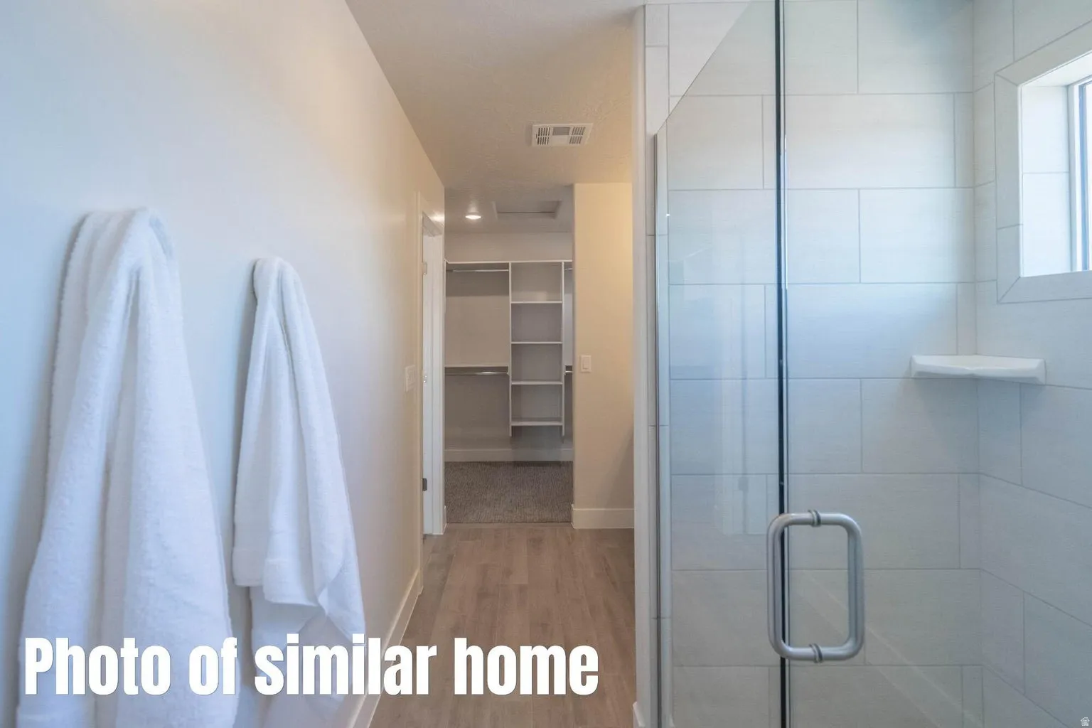 Glass-enclosed shower with subway tile surround, integrated shelving, and a window for natural light