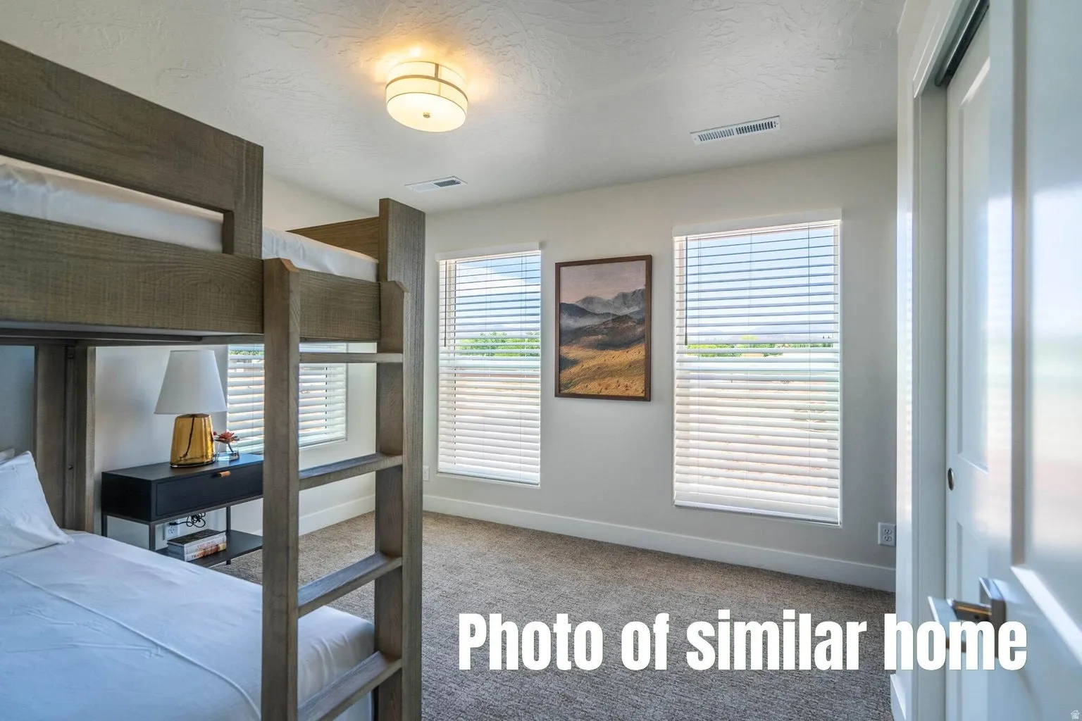 Carpeted flooring with dual windows featuring blinds, flush mount ceiling light, and a sliding door
