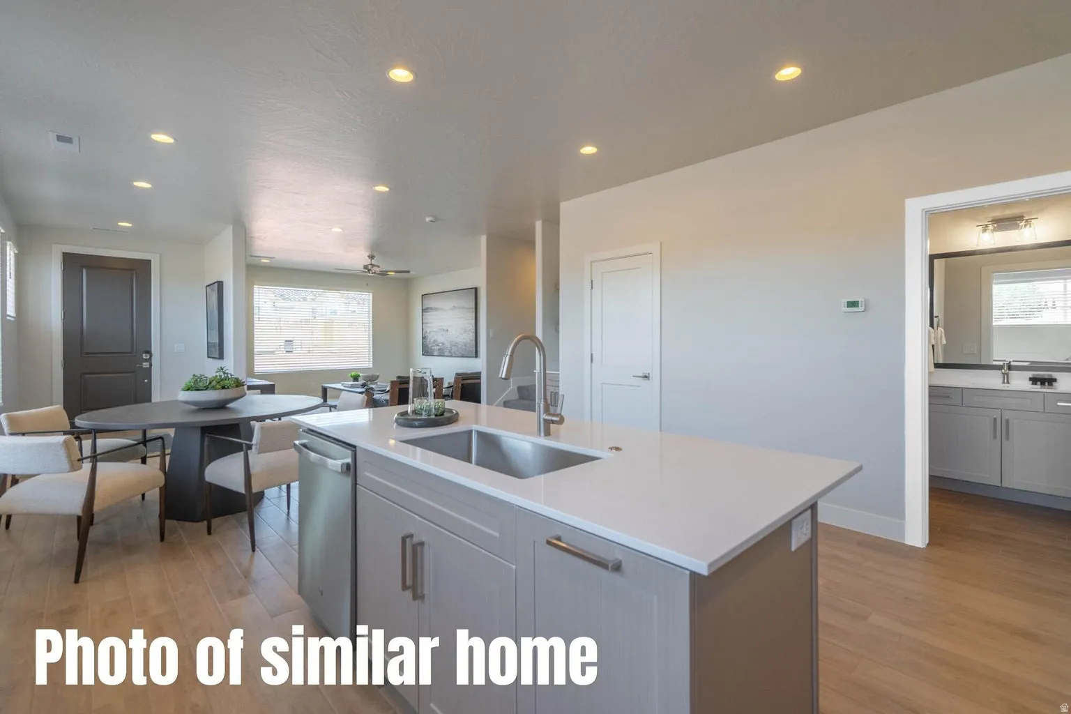 Kitchen island with a stainless steel sink, light gray cabinetry, and light-toned countertops