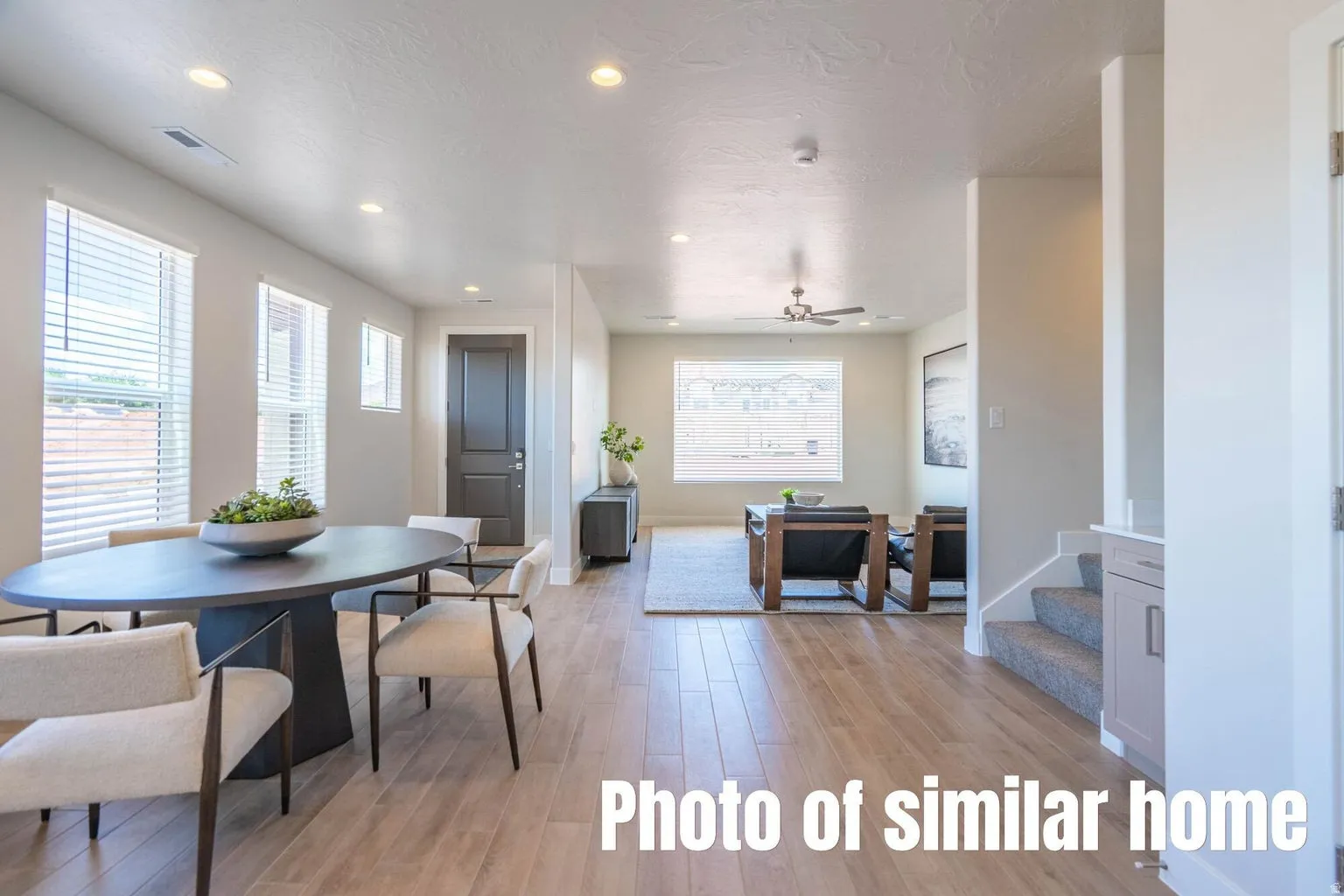Wood-finish flooring throughout, recessed lighting, multiple windows with blinds, and a ceiling fan in the living area