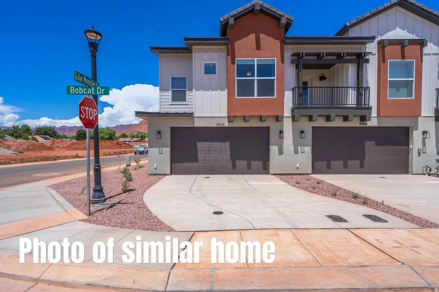 Contemporary multi-story exterior with stucco and siding accents, featuring a two-car garage, private balcony, and paved driveway with decorative rock landscaping