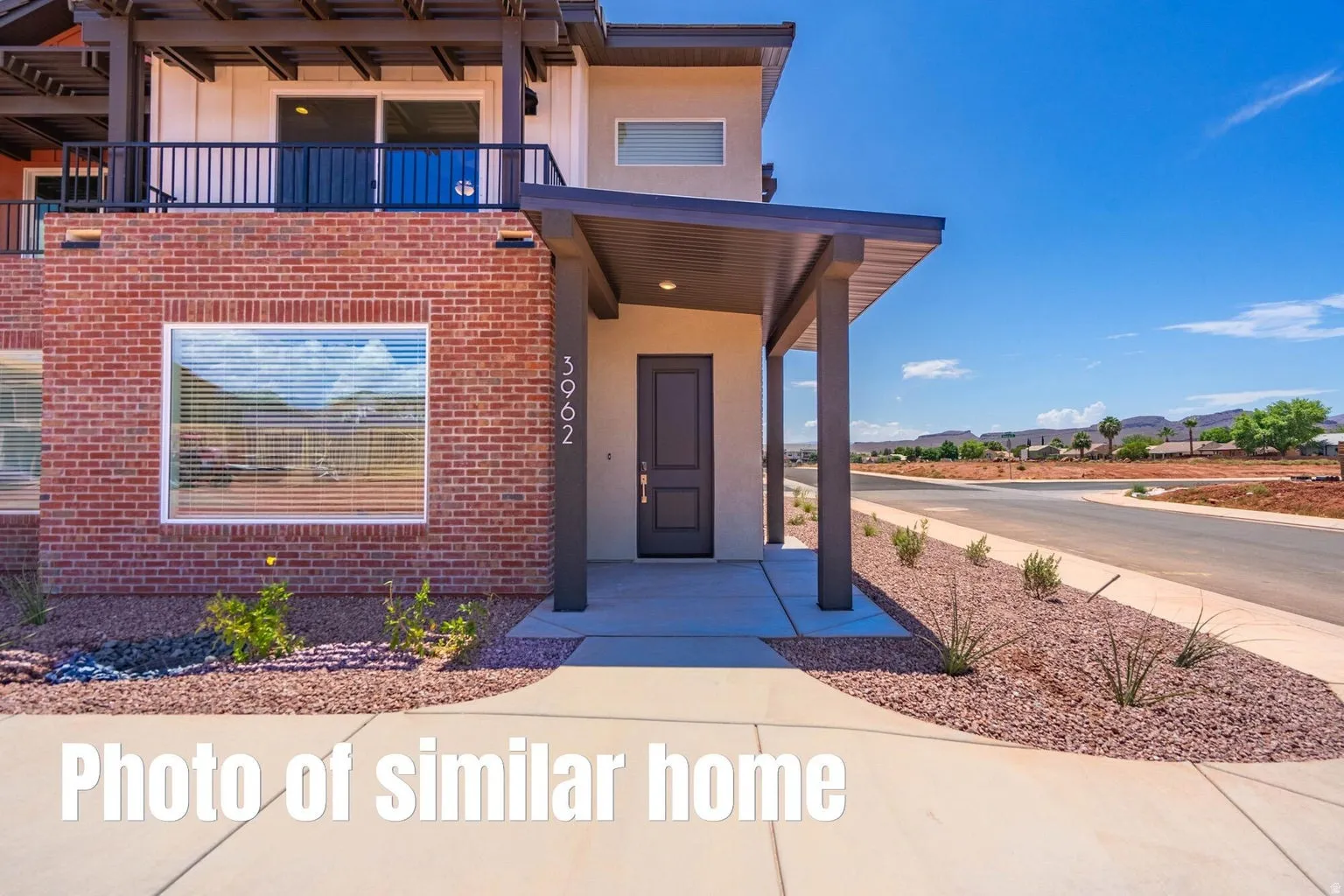 Brick exterior with a covered entryway, contemporary front door, and upper-level balcony with dark railing
