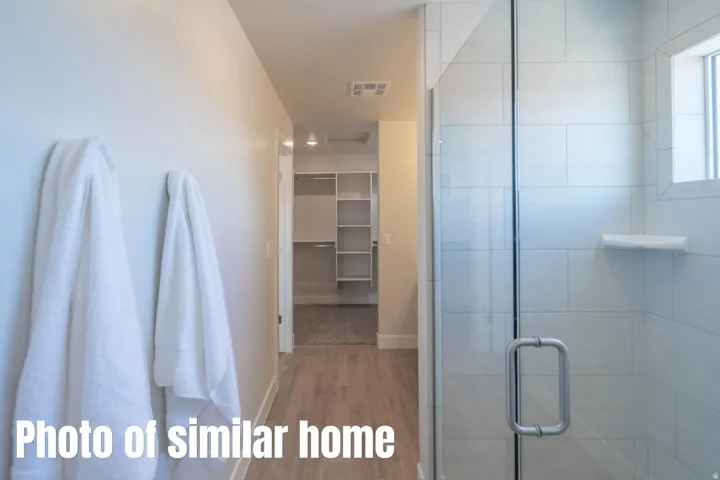 Glass-enclosed shower with subway tile surround, integrated shelving, and a window for natural light