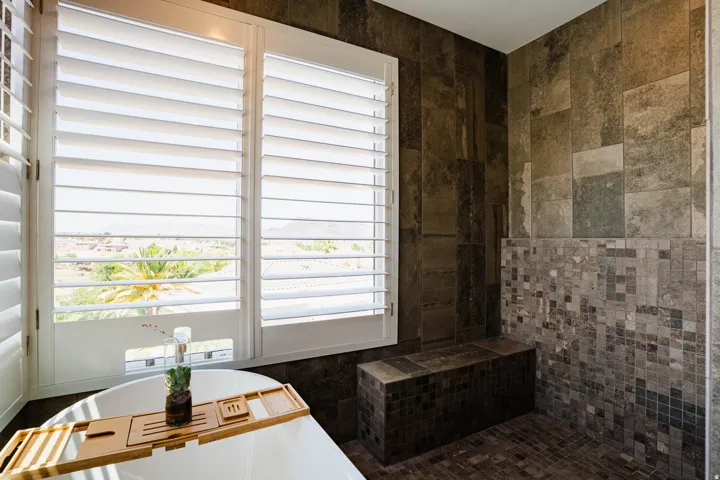 Freestanding soaking tub, white plantation shutters, large format tile shower walls, mosaic tile accent, and built-in shower bench