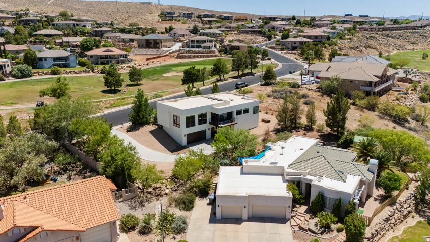 Hillside property with a multi-level structure, paved driveway, and established desert landscaping