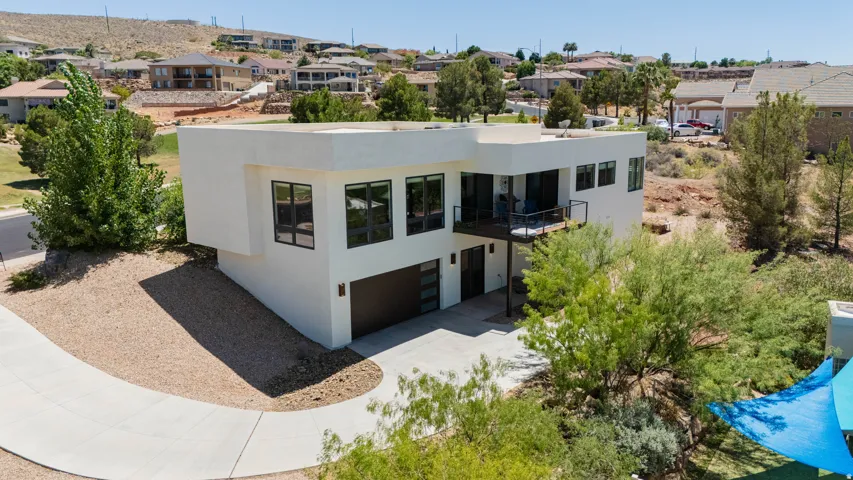 Contemporary architecture with a flat roofline, an integrated two-car garage, multiple large windows, and an upper-level balcony