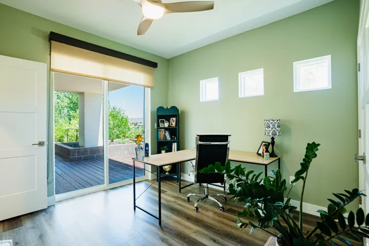 Wood-finish flooring, recessed windows, modern ceiling fan, and a sliding glass door opening to an outdoor deck with a built-in planter