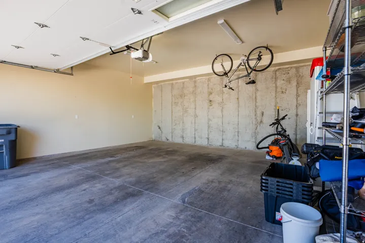 Spacious garage with concrete flooring, automatic garage door opener, overhead fluorescent lighting, and unfinished concrete wall