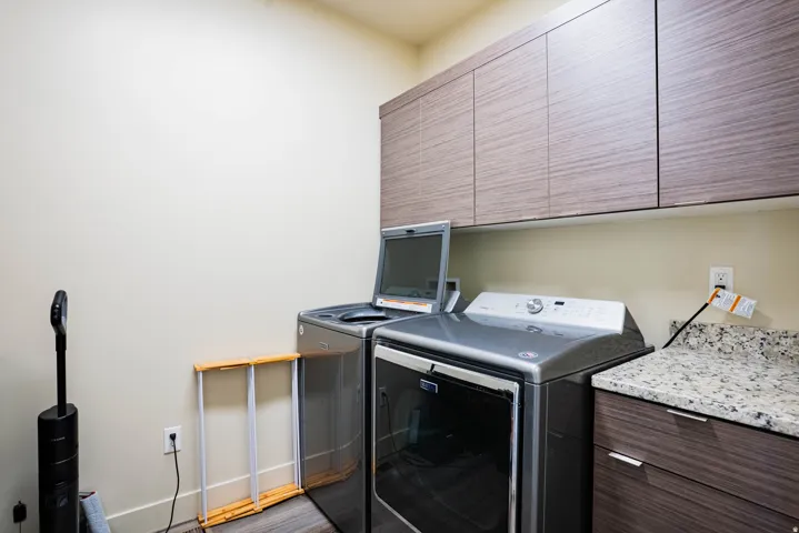 Laundry area featuring upper cabinetry, wood-finish flooring, and a stone-finish countertop