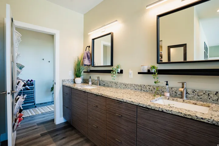 Dual vanity with wood-finish cabinetry, light-toned countertop, and integrated sinks