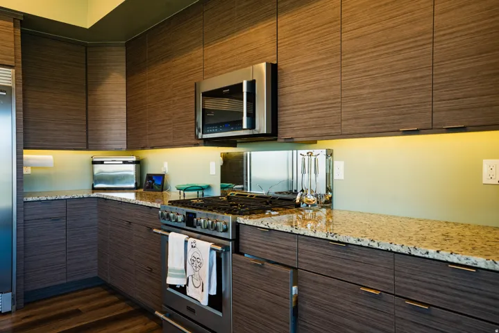 Kitchen featuring wood-finish cabinetry, stainless steel appliances, speckled stone countertops, and wood-finish flooring