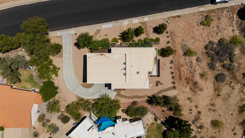Property features a paved driveway, flat roof, and natural landscaping