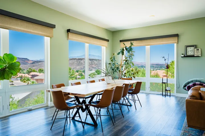 Spacious room with multiple large picture windows, light green wall finishes, and wood-finish flooring