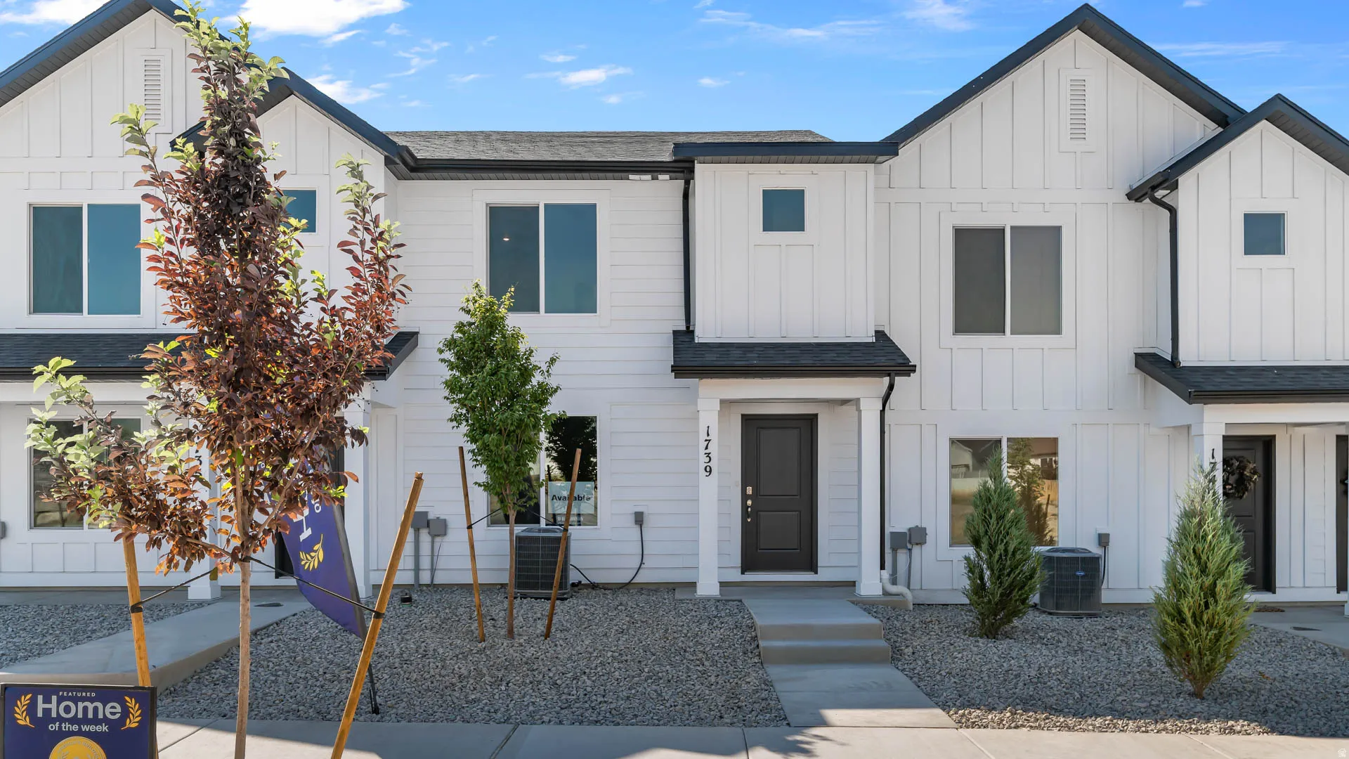 Modern farmhouse aesthetic featuring vertical white siding, dark trim, and a covered entry