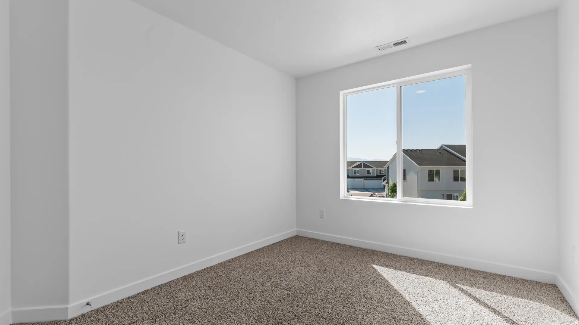 White walls with a single window, white trim, and light-colored carpet flooring