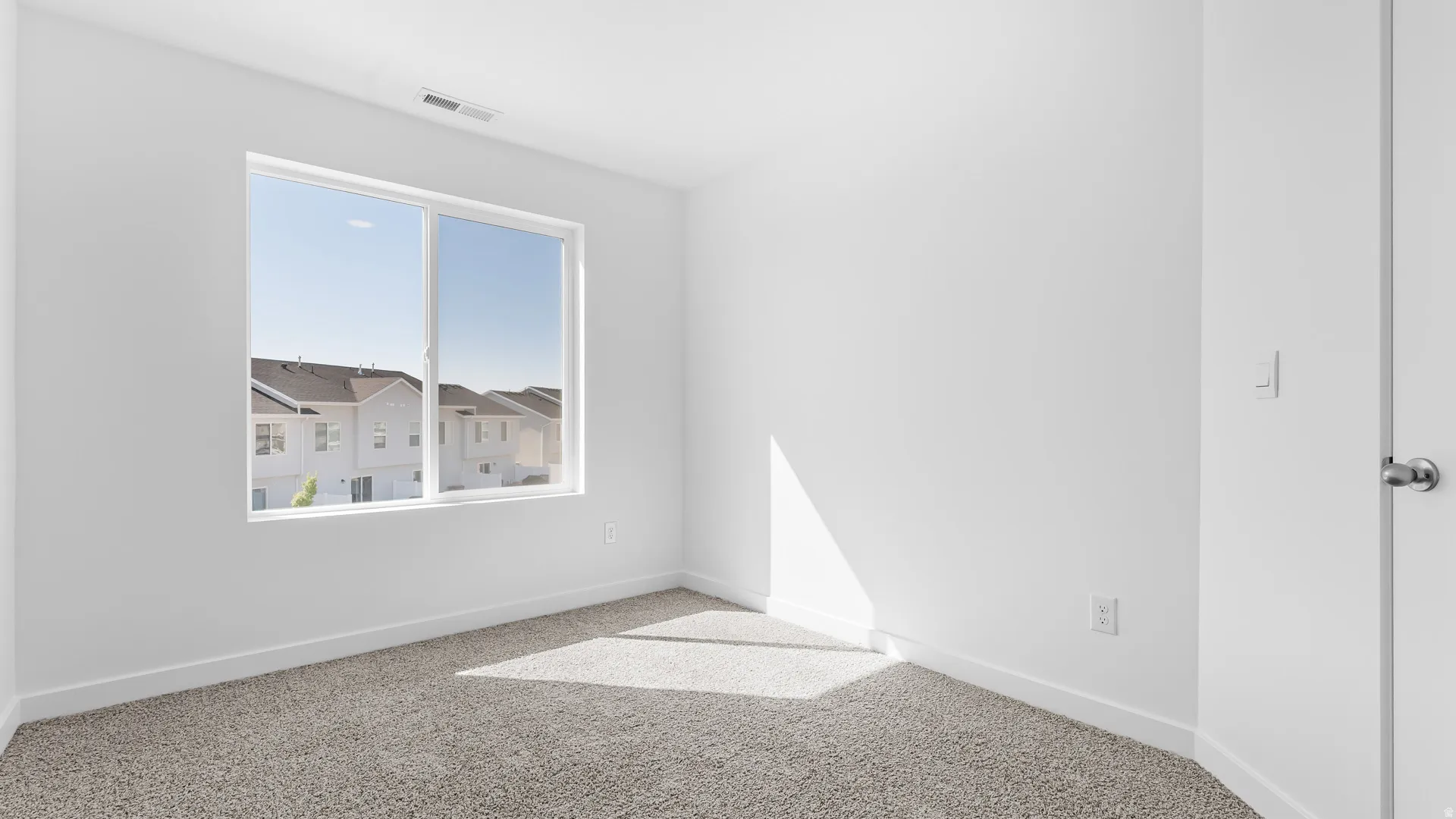 Large window, light-colored walls, light-colored carpeting, white trim