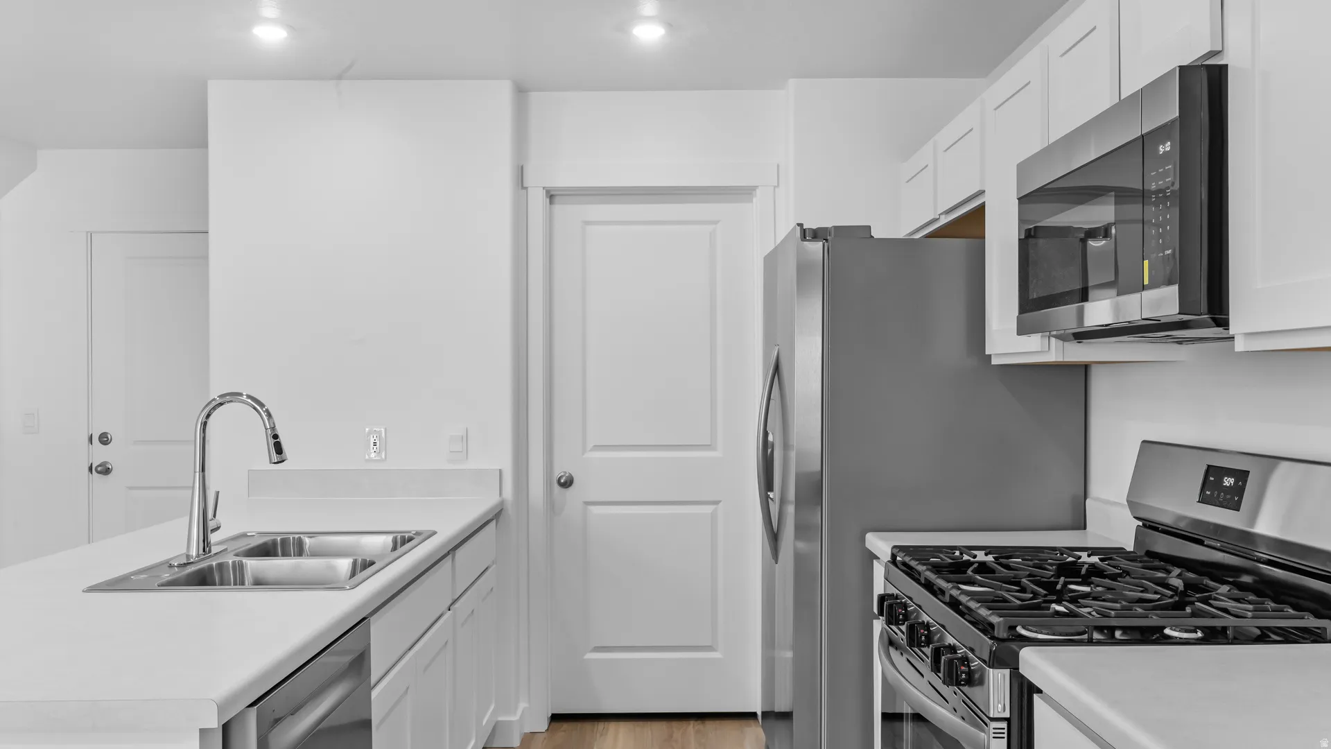 Modern kitchen featuring white cabinetry, light-toned countertops, a stainless steel gas range, and a stainless steel French door refrigerator