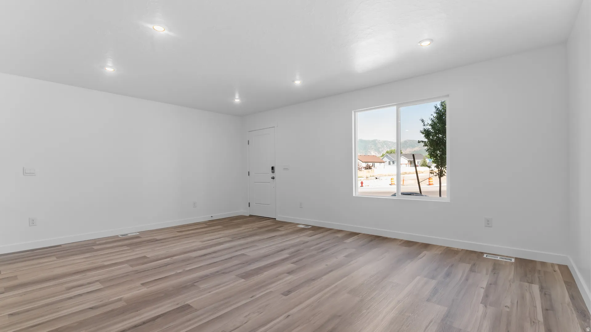 Recessed lighting, wood-finish flooring, white walls, and a large window