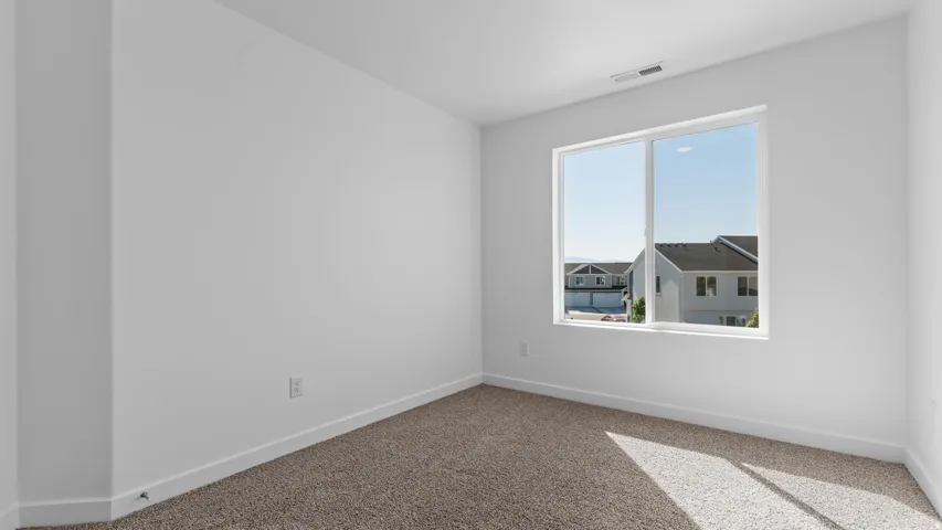 White walls with a single window, white trim, and light-colored carpet flooring