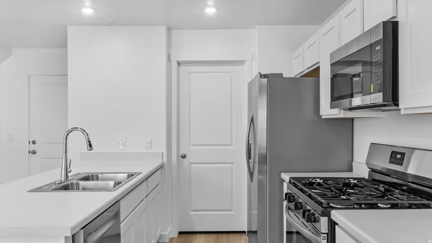Modern kitchen featuring white cabinetry, light-toned countertops, a stainless steel gas range, and a stainless steel French door refrigerator