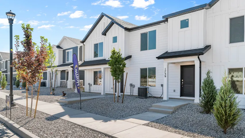 Modern townhome with white vertical siding, dark trim, and a covered entryway