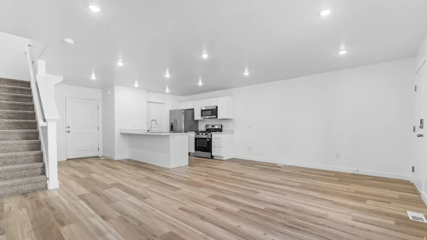 Open-concept living space with wood-finish flooring, white walls, and recessed lighting