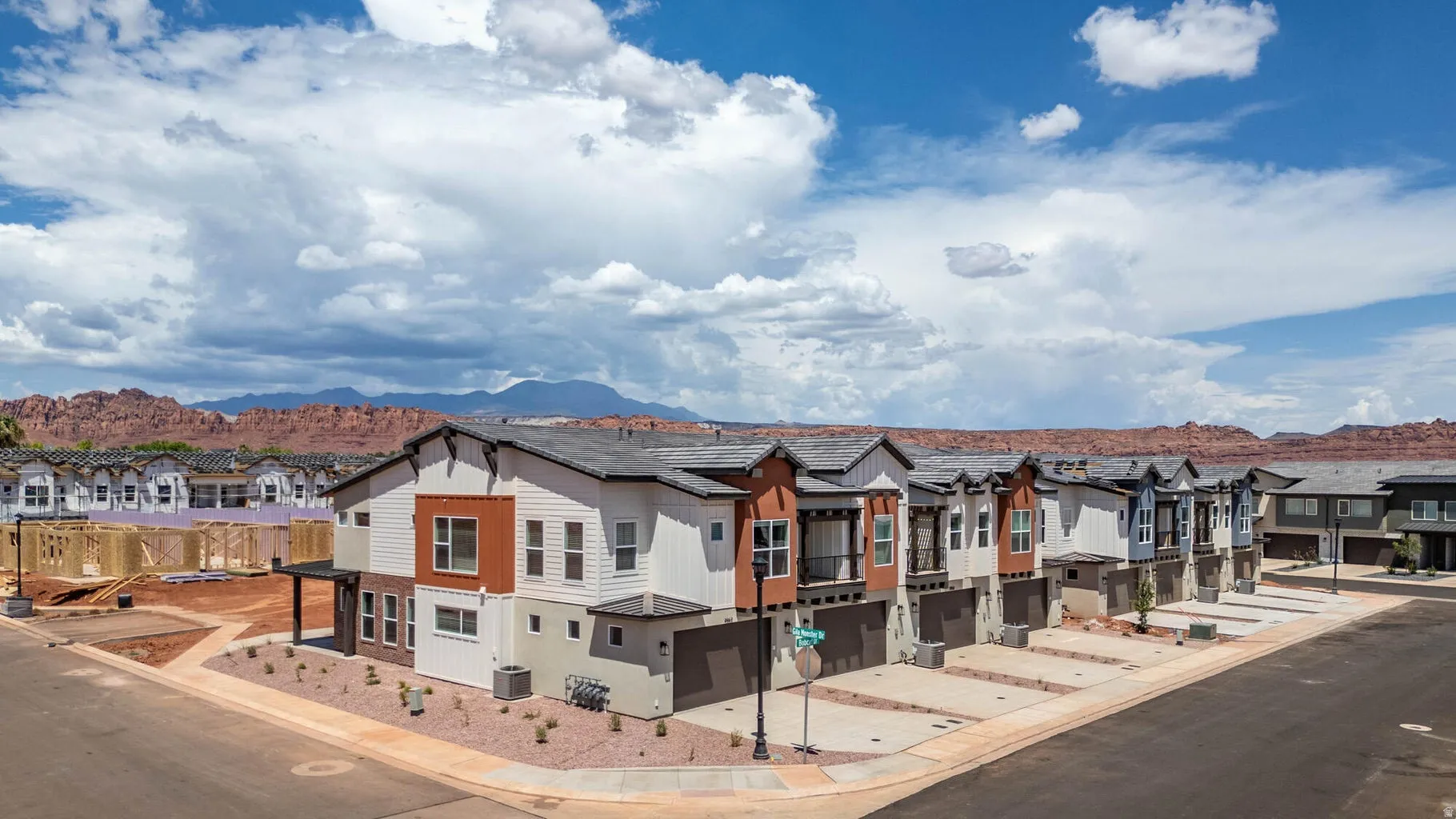 Contemporary townhome architecture featuring varied exterior finishes, attached garages, and a paved street