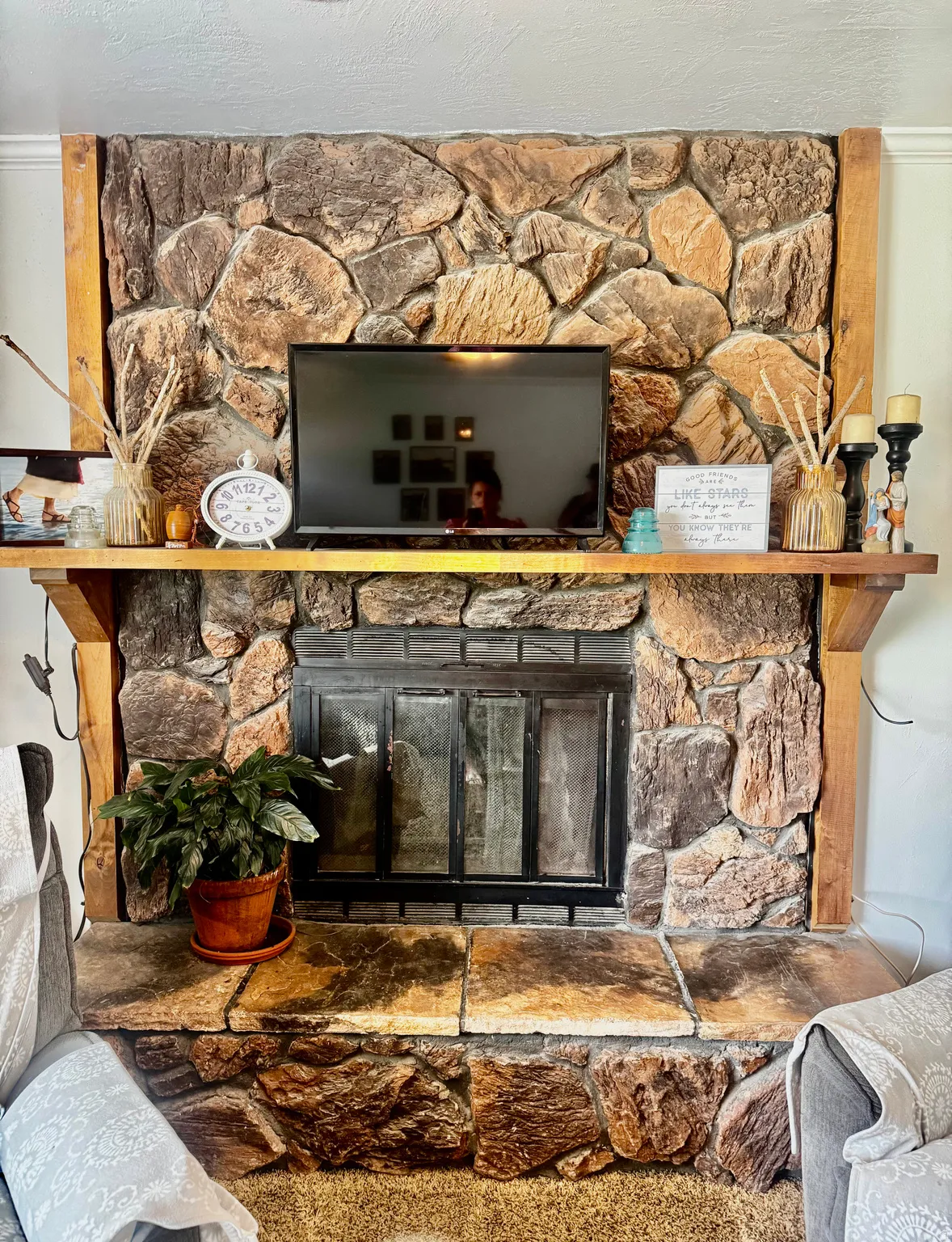 Stone-clad fireplace with a wood mantel and hearth, featuring an integrated firebox with glass doors