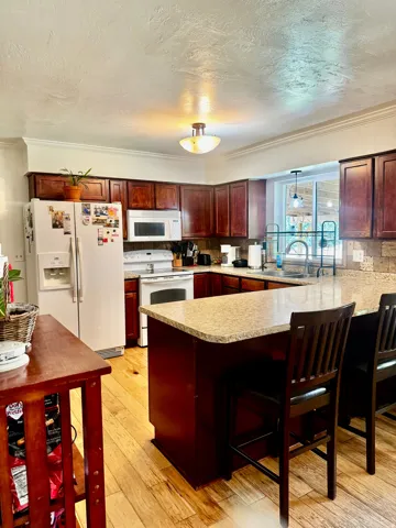 Cherry wood-finish cabinetry, light-toned wood-finish flooring, and a stone-look countertop