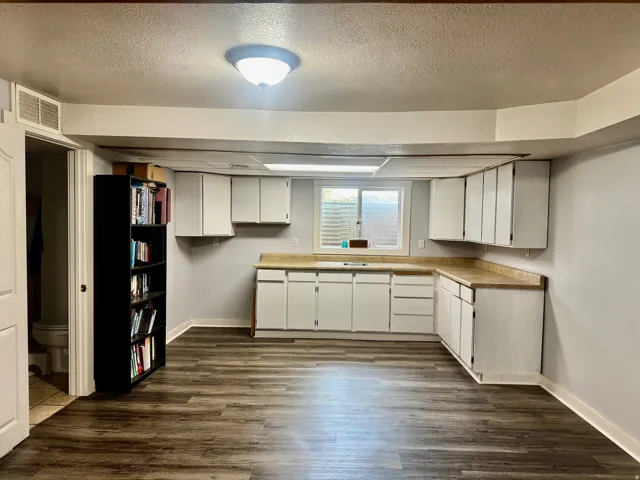 Wood-finish flooring, white cabinetry, light-toned countertops, and an integrated ceiling light fixture