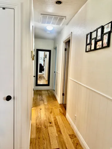 Hardwood flooring, vertical paneling detail on walls, white door frames, and white doors