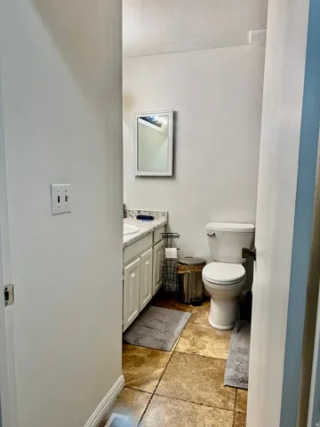 White vanity with cabinet storage, countertop, undermount sink, and wall-mounted mirror