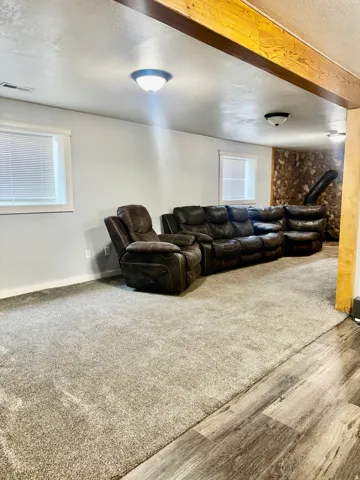 Spacious room featuring wood-finish flooring, plush carpeting, and recessed windows